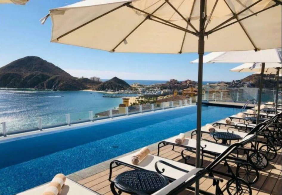 A swimming pool with chairs and umbrellas overlooking the ocean