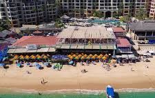 An aerial view of a beach with a large building in the background.