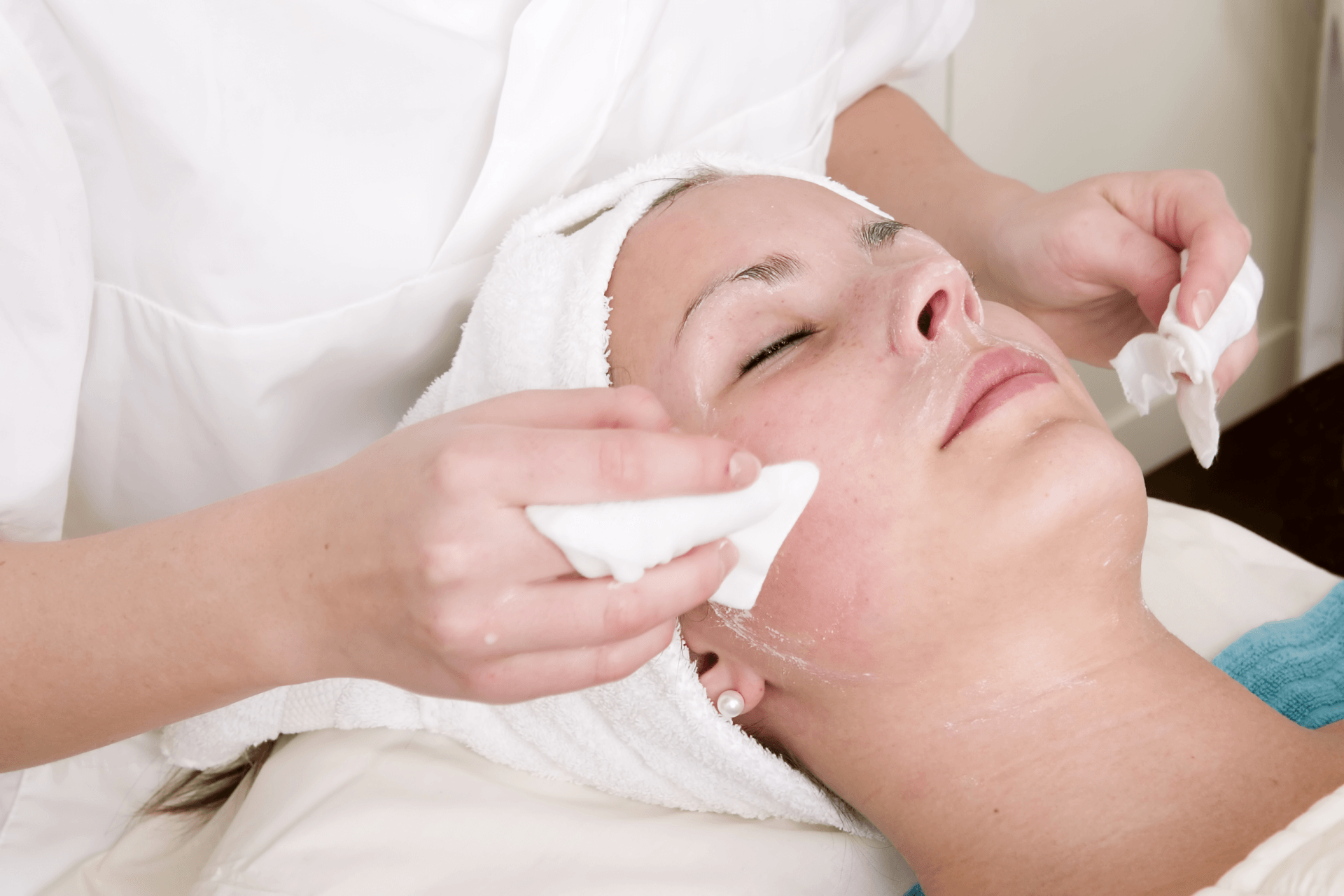 A woman with a towel on her head is getting a facial treatment