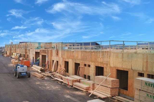 A building under construction with a lot of wood on the ground.