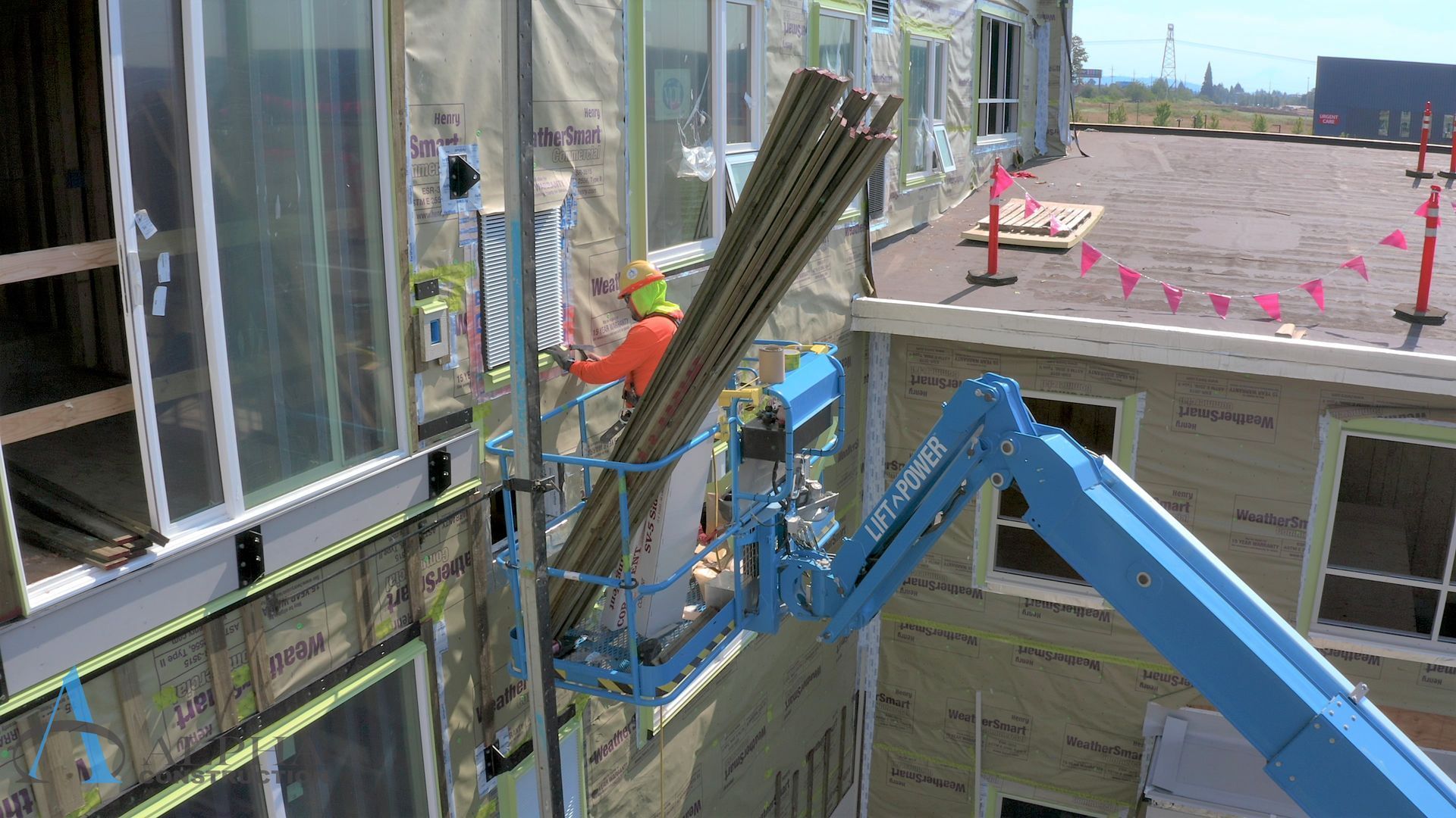 A man is standing on a crane holding a stack of wood.