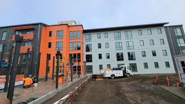 A large building under construction with a white truck parked in front of it.