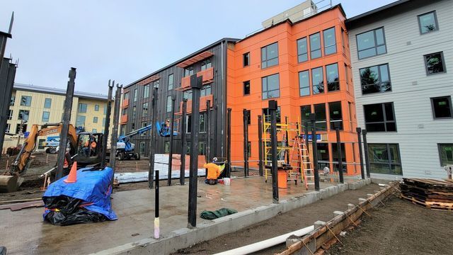 A large orange building is being built next to a smaller building.