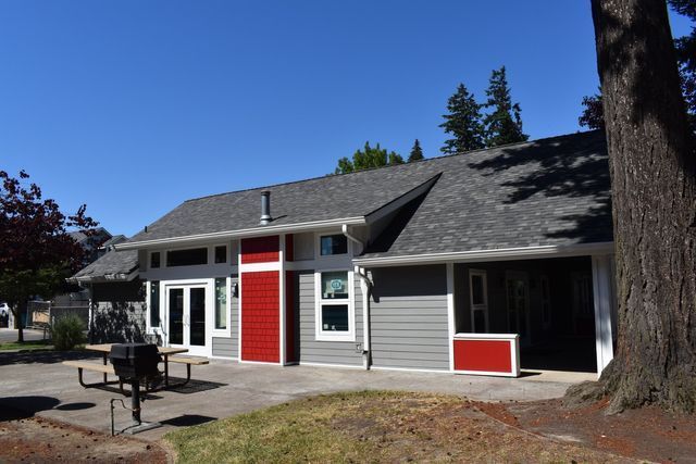 A gray and red house with a picnic table in front of it