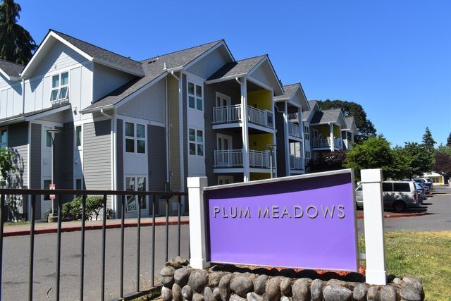 Plum meadows apartment building with a purple sign in front of it