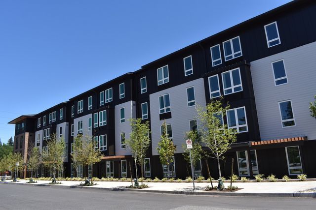 A large apartment building with a lot of windows and trees in front of it.