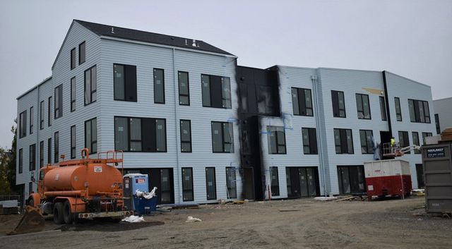 A large building under construction with a tanker truck parked in front of it.