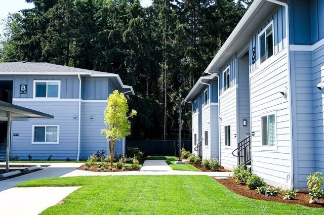 A row of apartment buildings with a lush green lawn in front of them