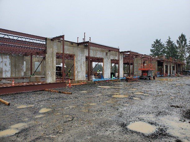 A large building is being built in a muddy area.
