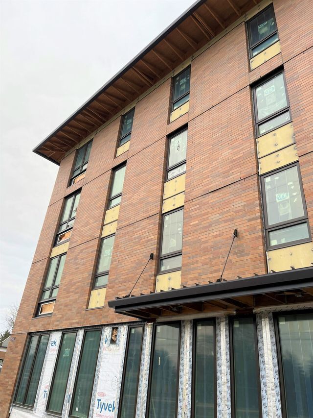 A large brick building with a lot of windows is under construction.