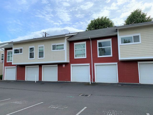 A row of apartment buildings with red siding and white garage doors.