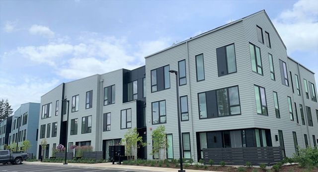 A large apartment building with a lot of windows and a car parked in front of it.