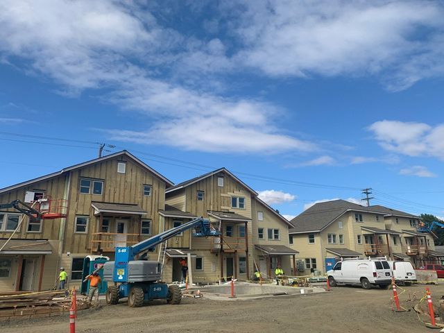 A row of houses under construction with a blue sky in the background.