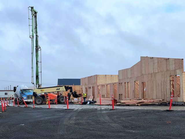 A concrete pump is being used to pour concrete into a building under construction.