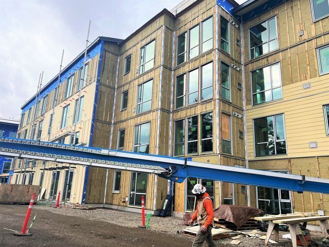 A man is standing in front of a large building under construction.