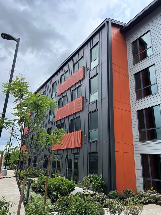 A large building with a lot of windows and trees in front of it.