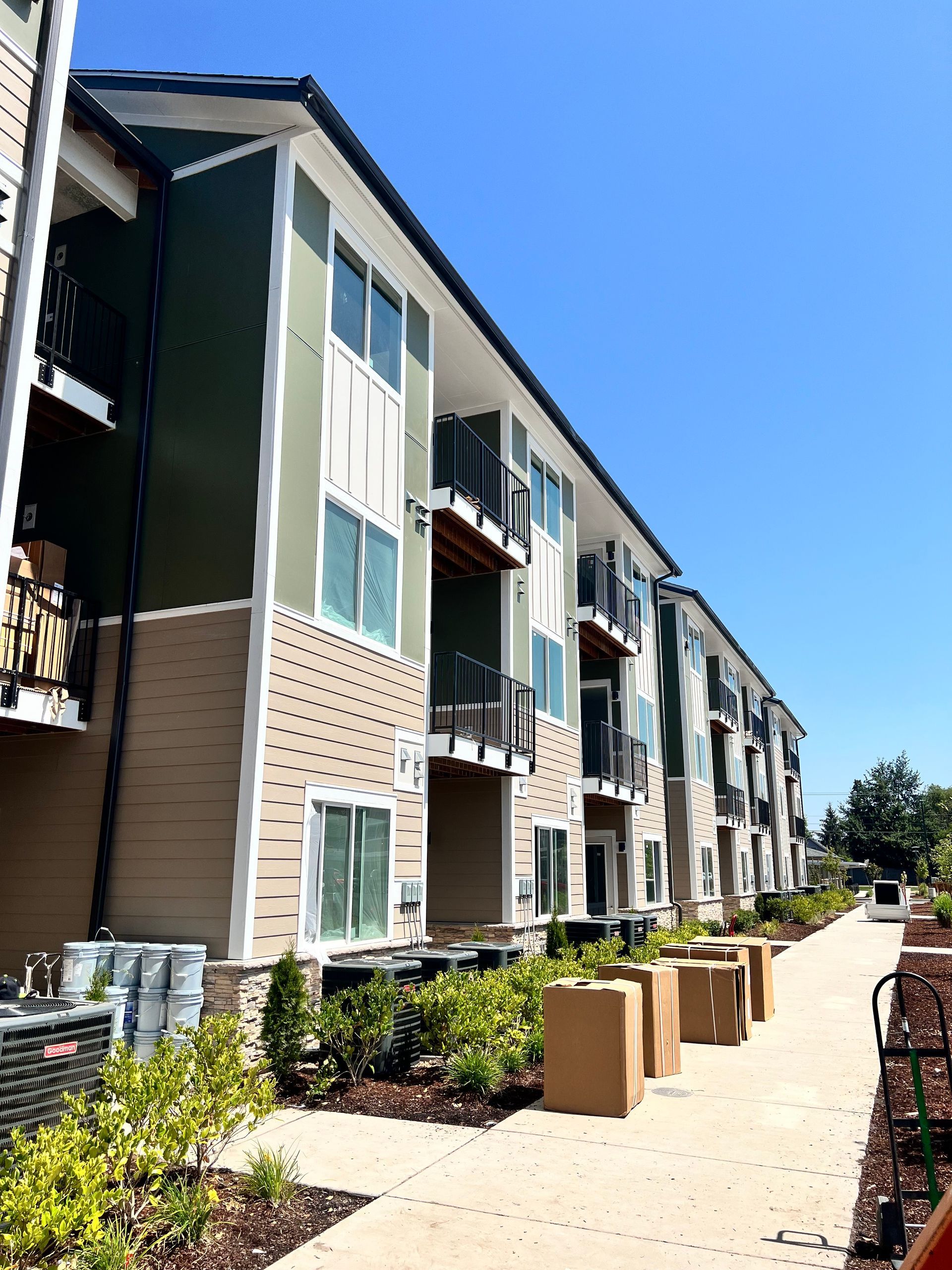 A large apartment building with boxes on the sidewalk in front of it.
