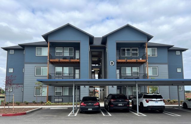 A blue apartment building with cars parked in front of it.