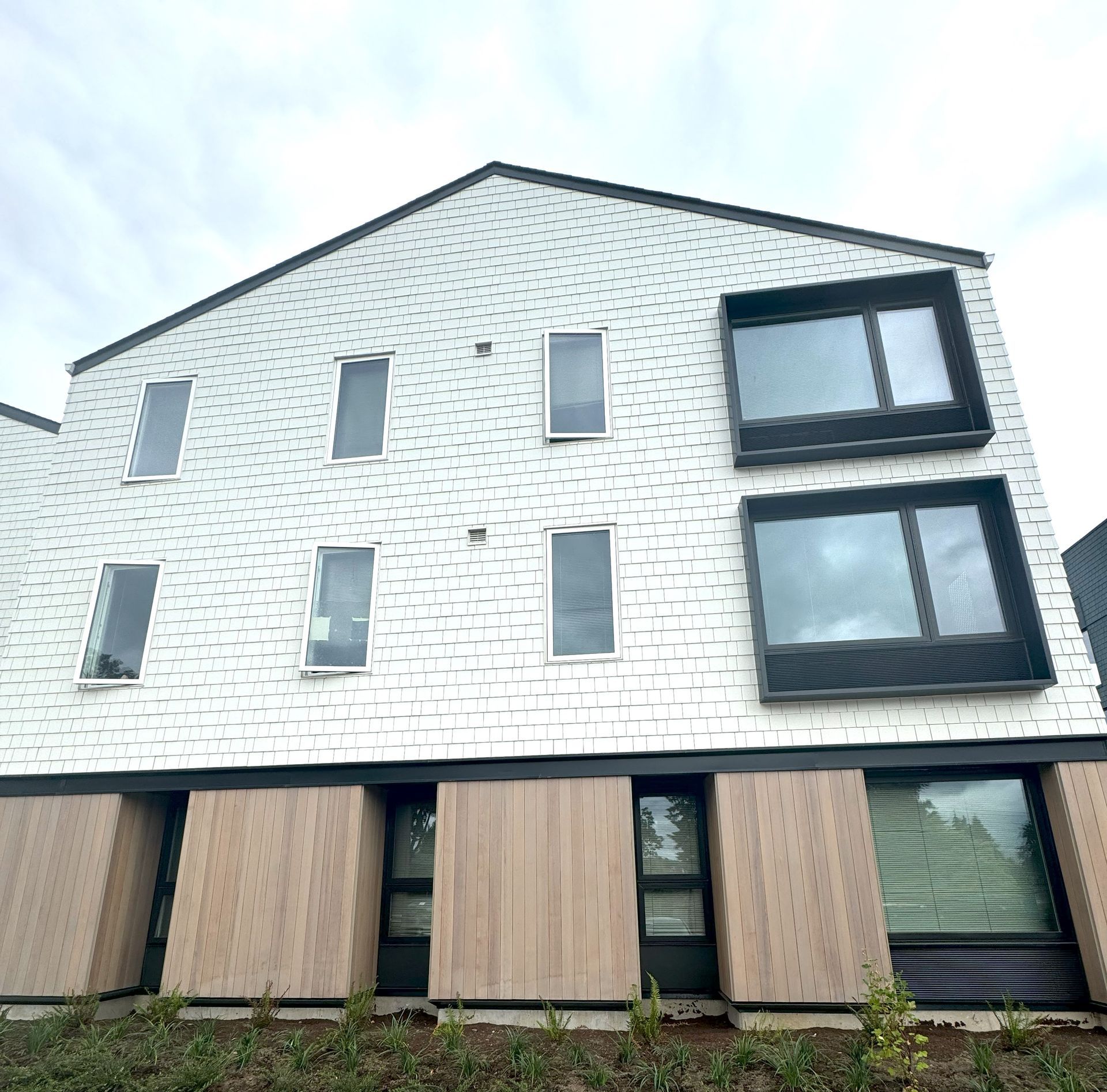 A large white brick building with a lot of windows and wooden doors.