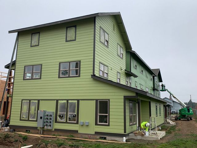 A large green building with a lot of windows is being built.