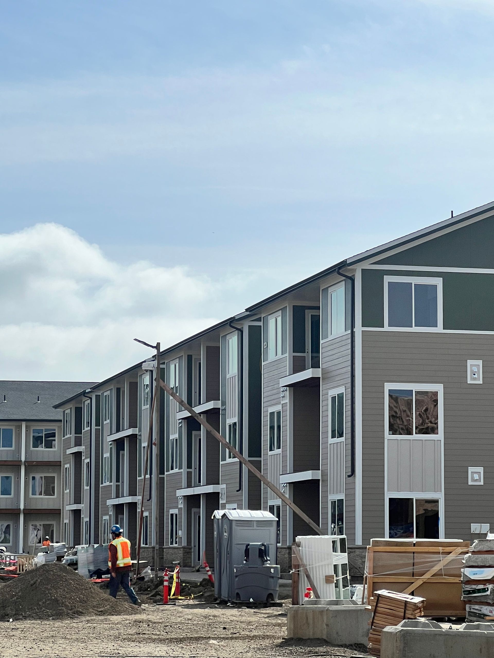 A row of apartment buildings are under construction on a sunny day