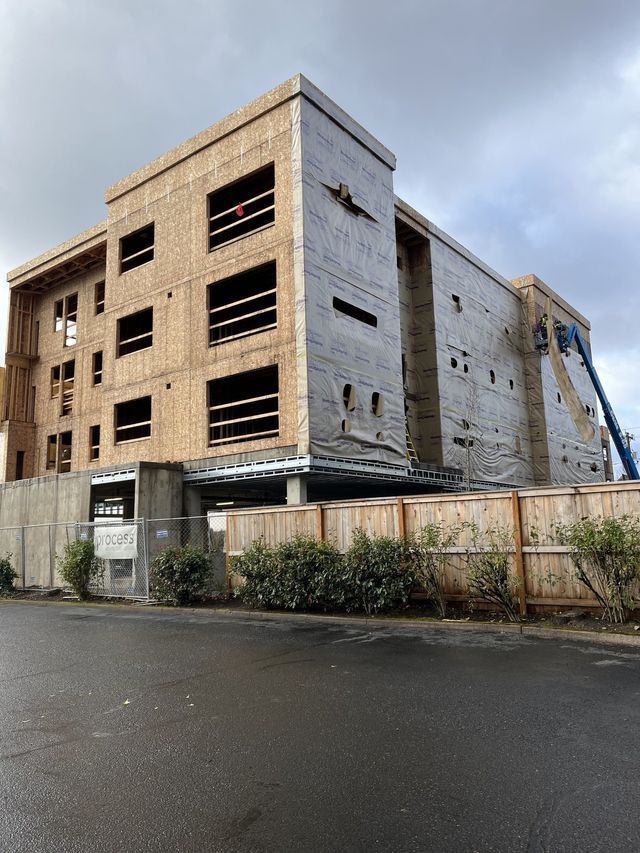 A large building is being built next to a wooden fence.