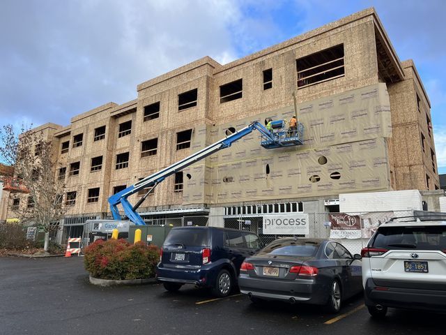 A building under construction with cars parked in front of it.