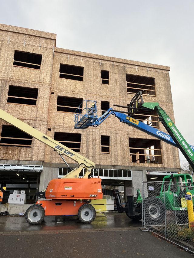 A large building under construction with a jlg lift in front of it