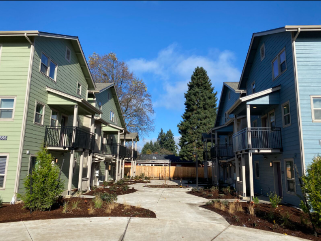 A row of apartment buildings with green and blue siding
