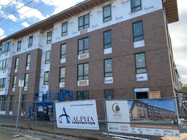 A large brick building under construction with a fence around it.