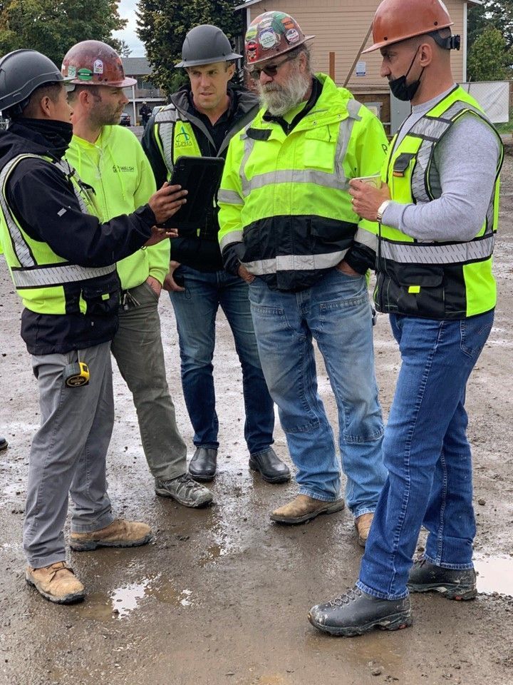 A group of construction workers are standing around talking to each other.