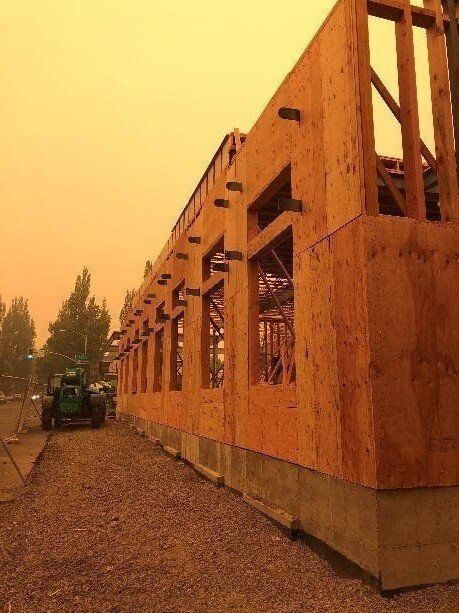 A tractor is driving past a building under construction.