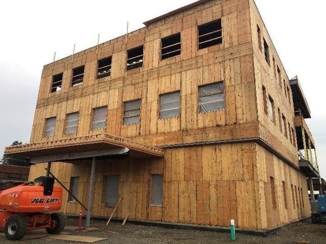 A large wooden building is being built with a crane in front of it.