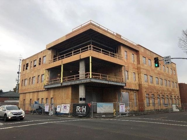 A large building is being built on the corner of a street.