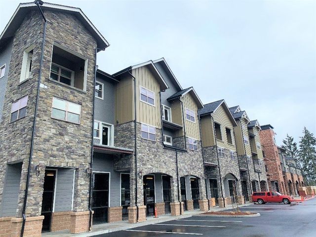 A row of apartment buildings with a red car parked in front of them.