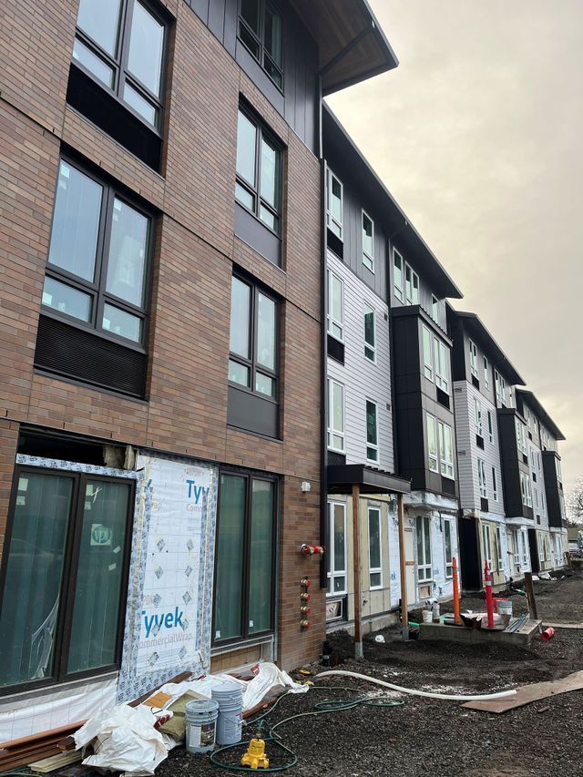 A large brick building with a lot of windows is under construction.