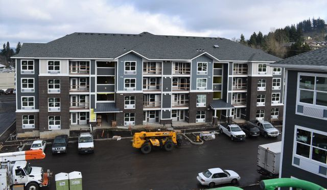 A large apartment building with a lot of cars parked in front of it
