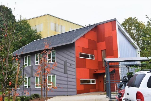 A red and gray building with a car parked in front of it