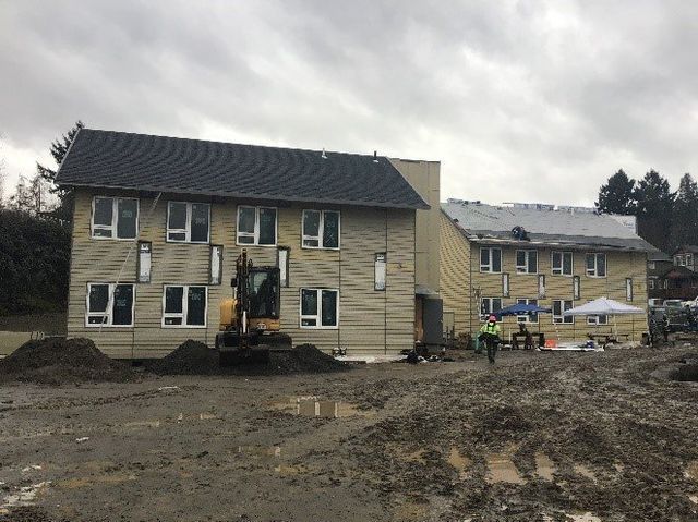 A construction site with a building under construction and a bulldozer in front of it.