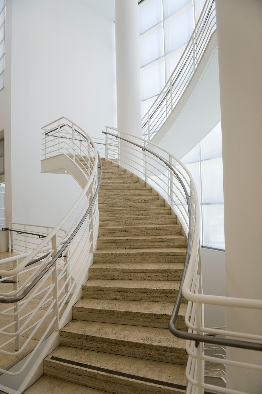 A spiral staircase with a white railing in a building