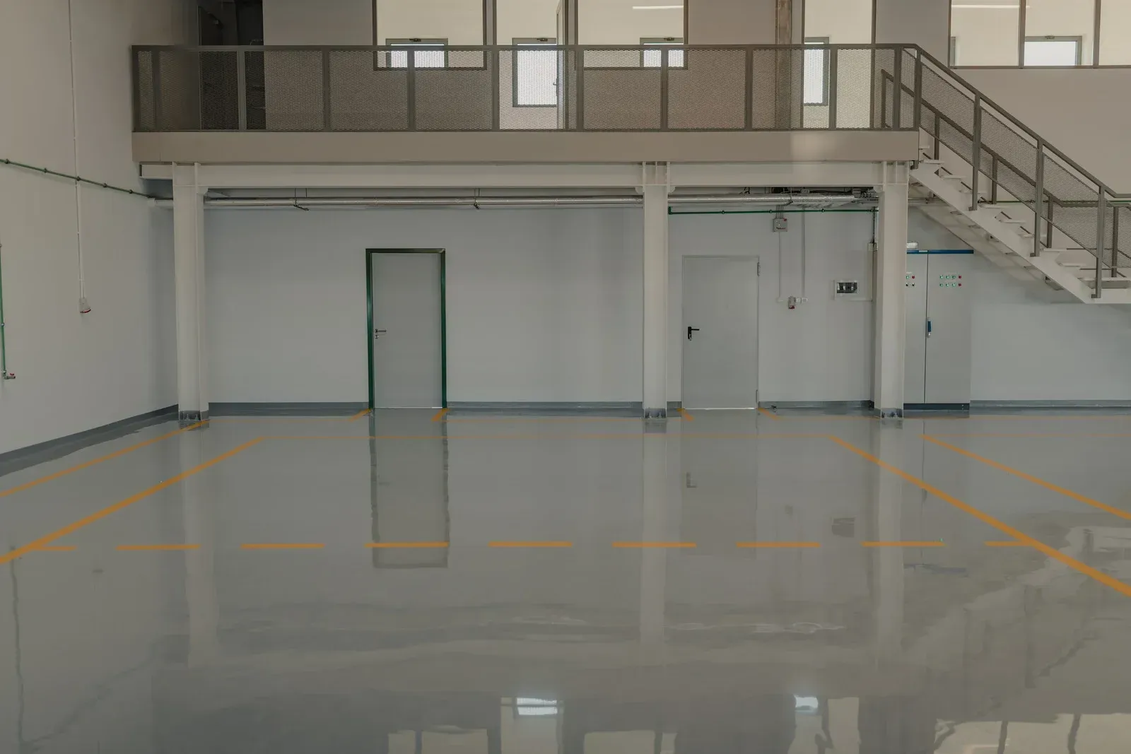 A large empty warehouse with a balcony and stairs.