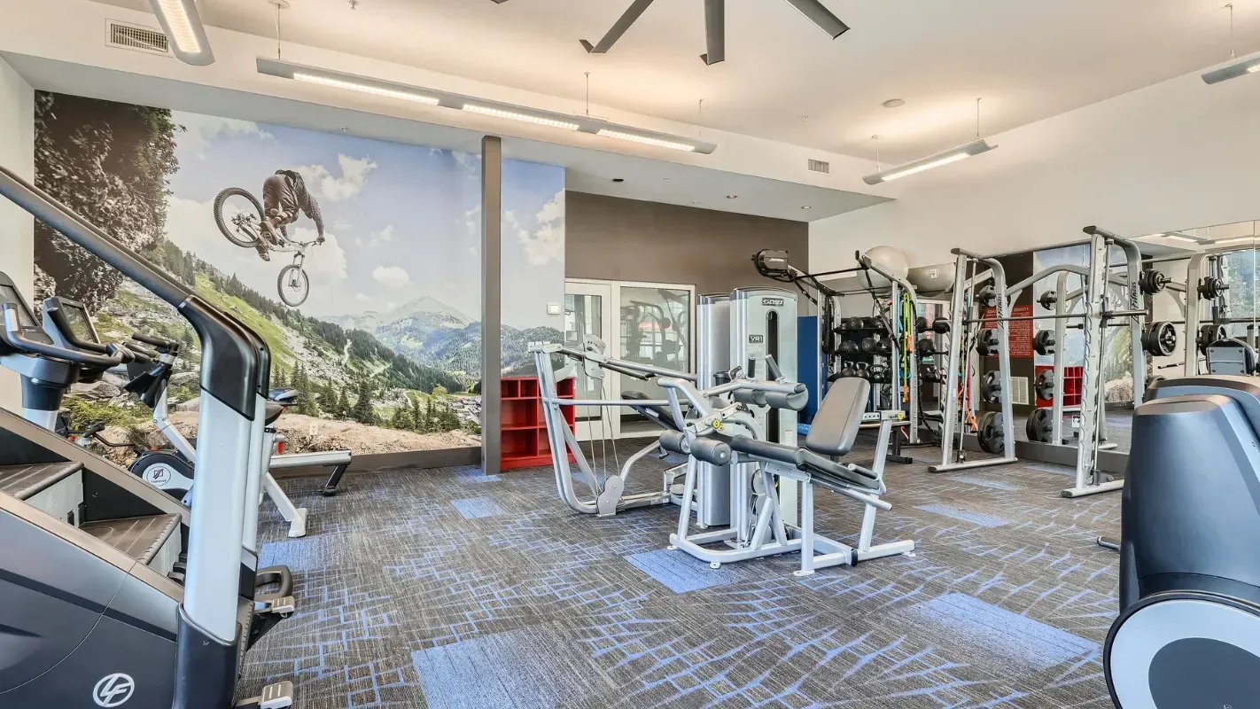 Fitness center interior featuring cardio machines, weight machines, and benches.