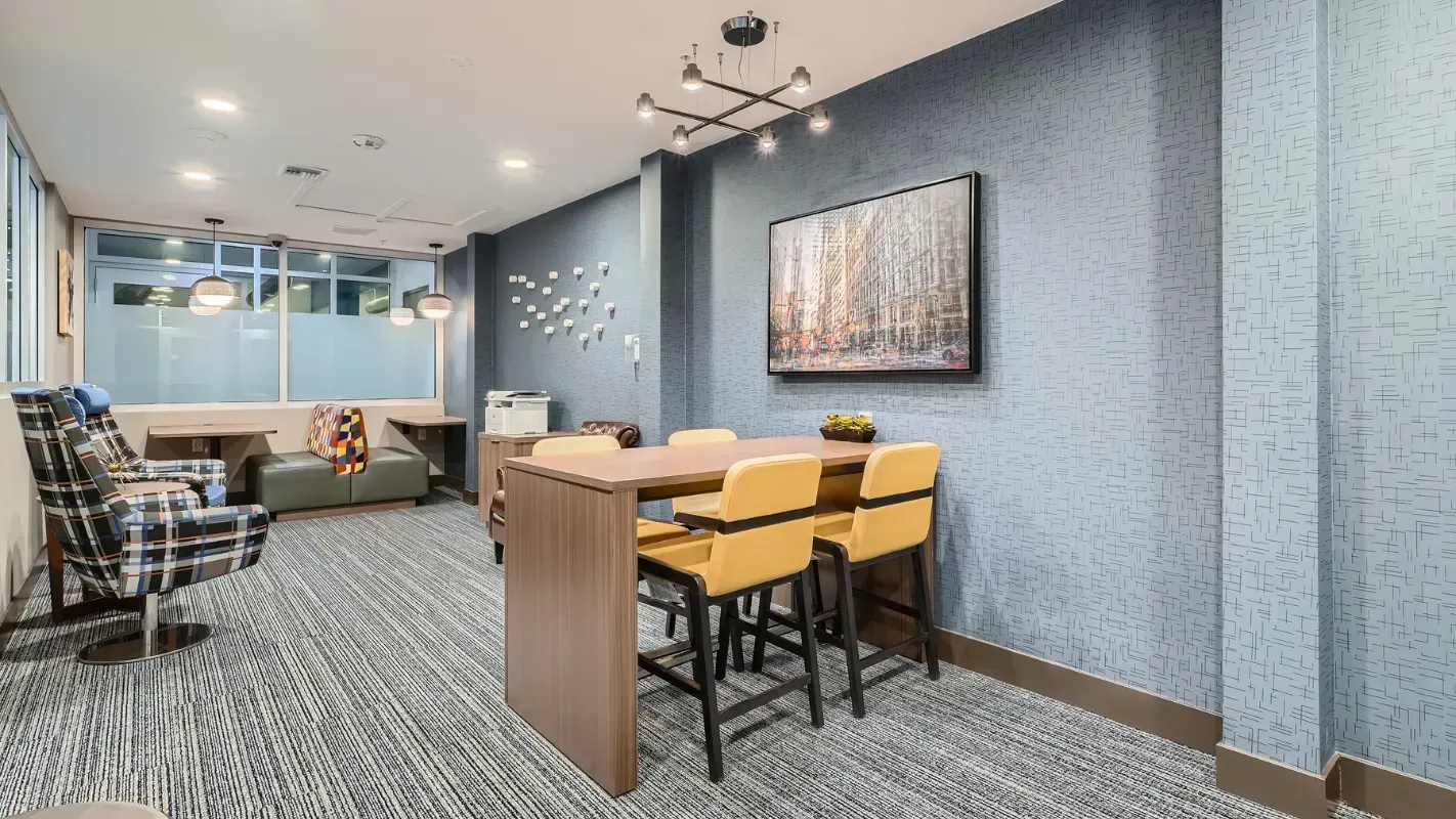 Interior of a modern apartment community lounge with a high-top table and yellow chairs