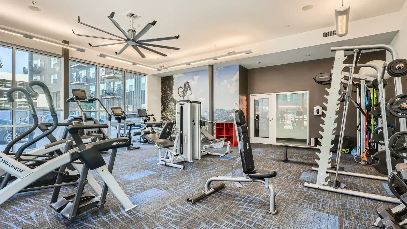 Indoor community gym with cardio machines, weight benches, and free weights.