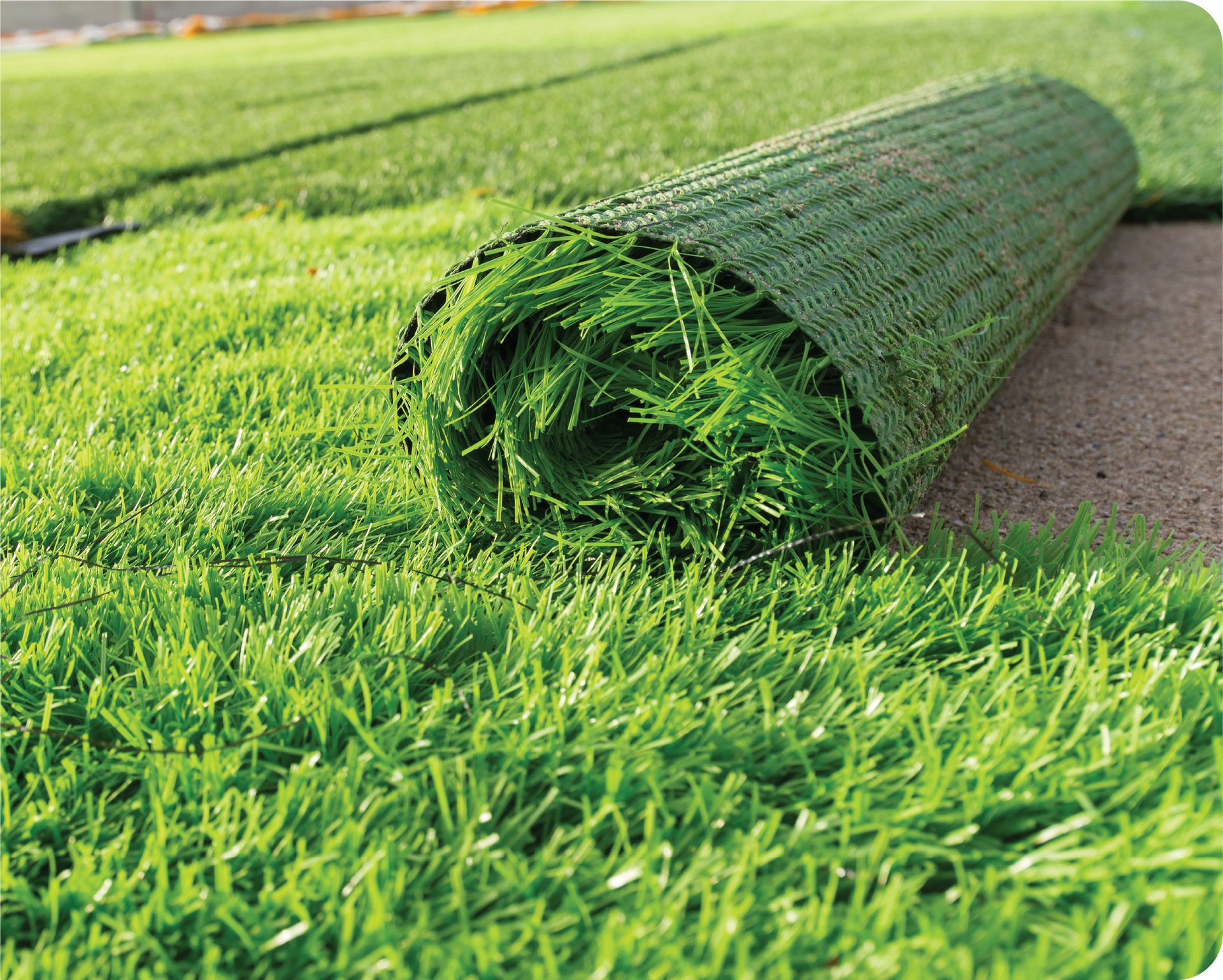 A roll of artificial grass is sitting on top of a lush green field.