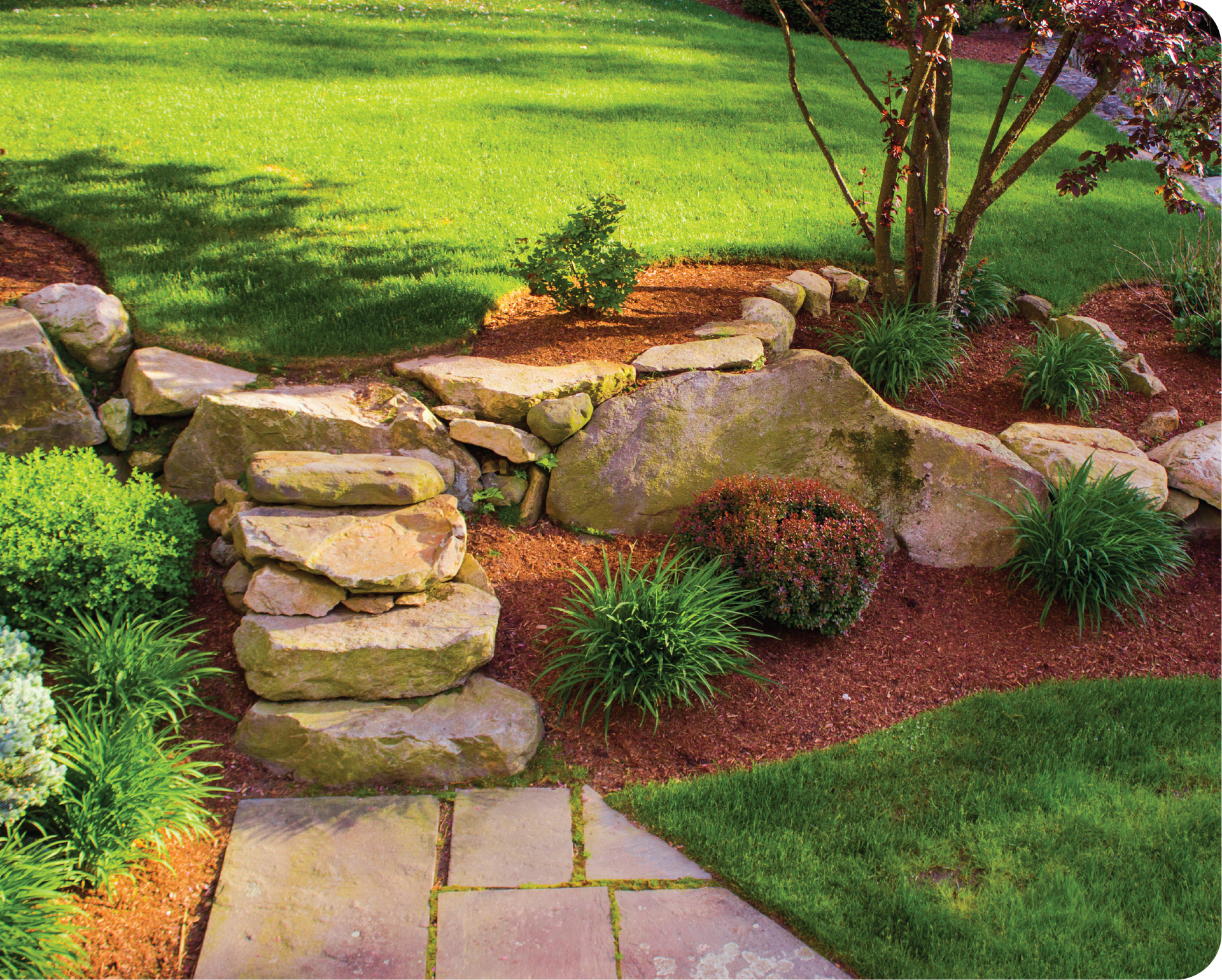 A stone walkway leading to a lush green lawn