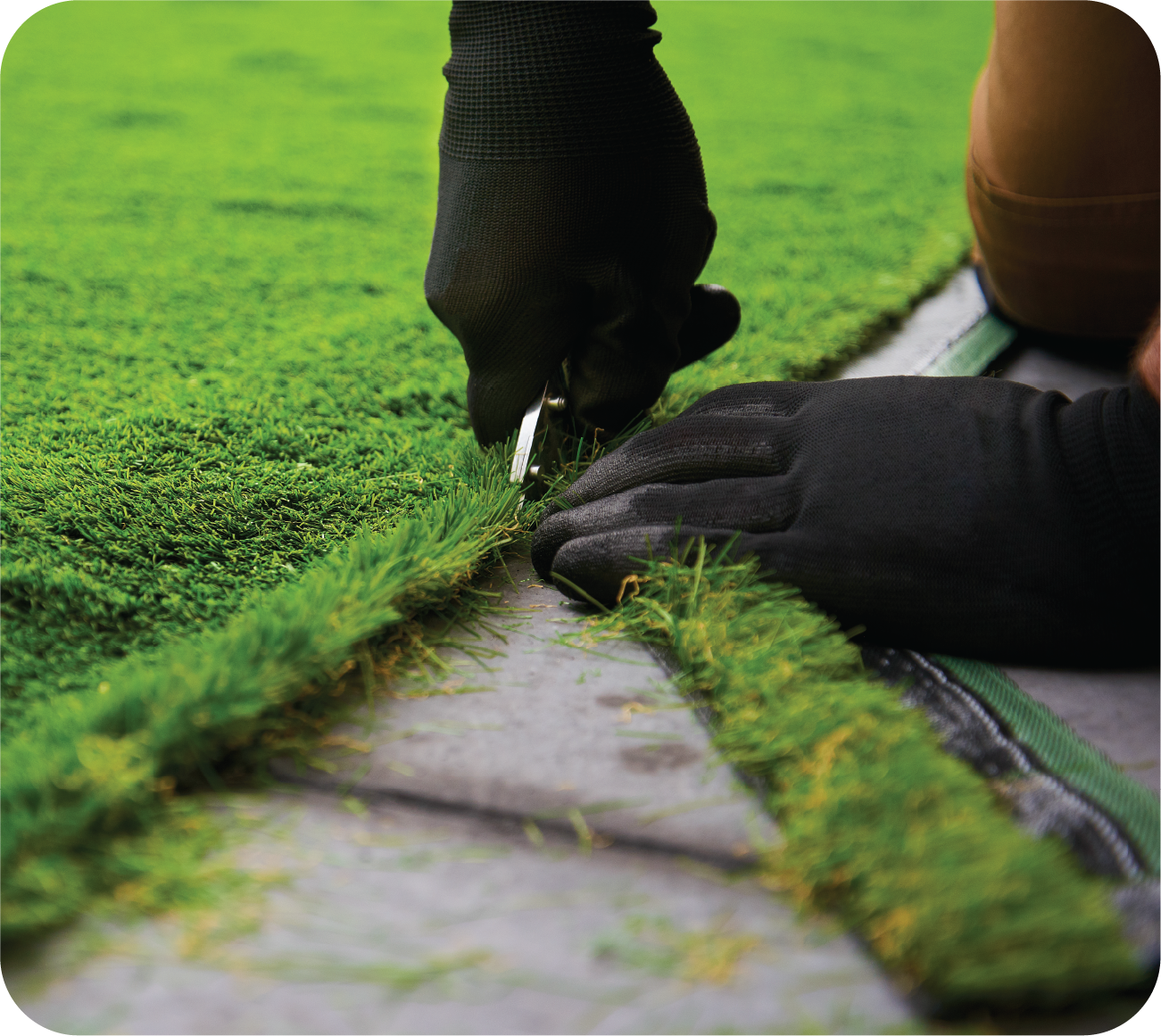 A person is cutting a piece of artificial grass with a pair of scissors.