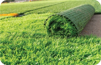 A roll of artificial grass is sitting on top of a lush green field.