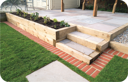 A wooden planter with steps leading up to a patio.