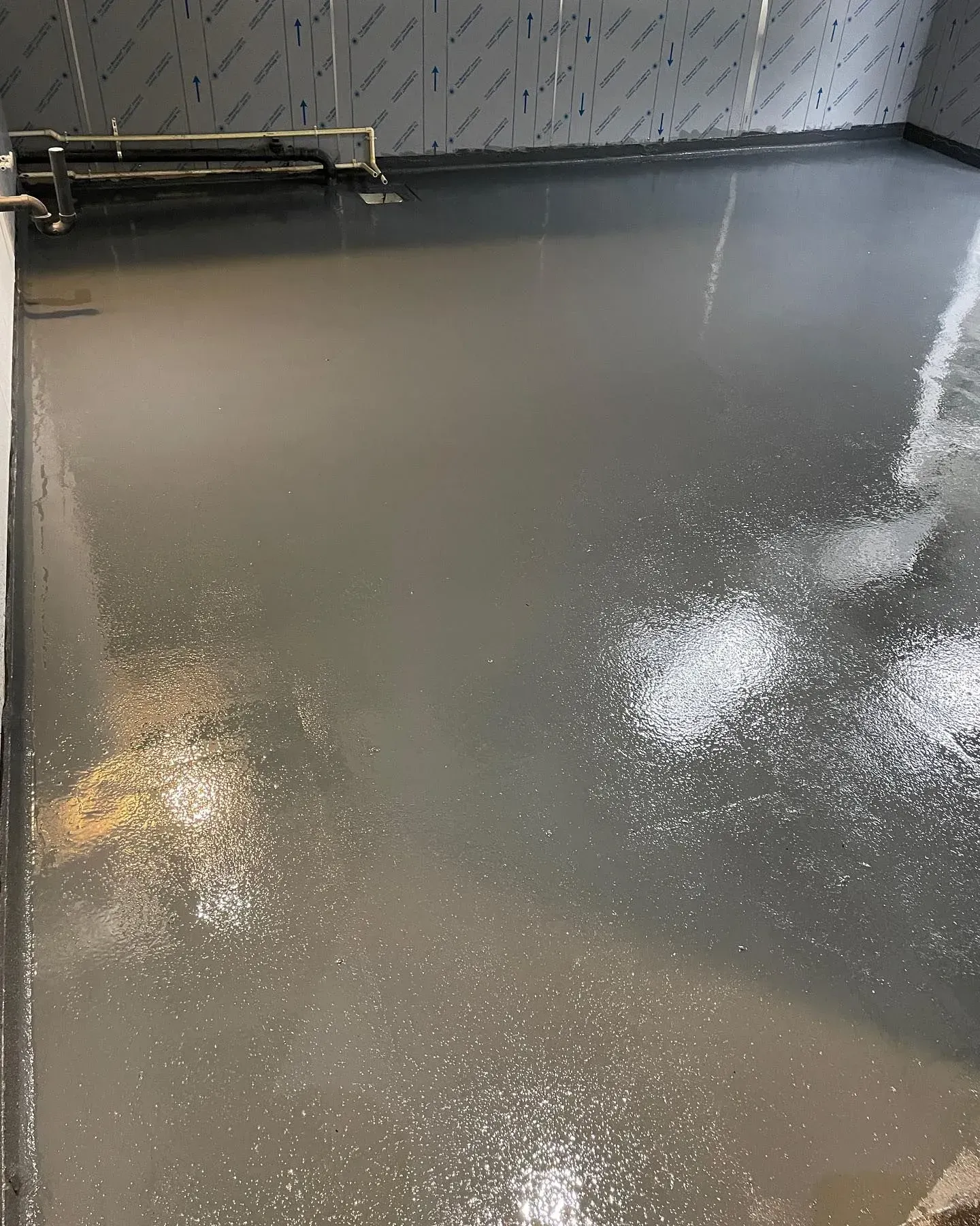 Gray industrial floor with splashes of white, reflecting light in a room.